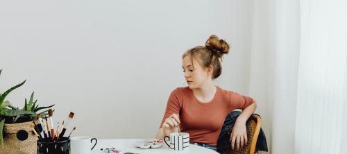 Female artist sitting thoughtfully while looking at her artwork - 592721