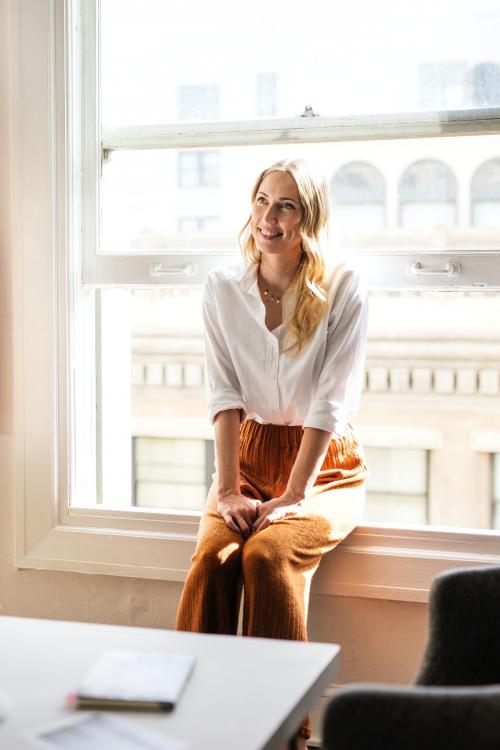 Happy woman sitting on a window sill - 1220766