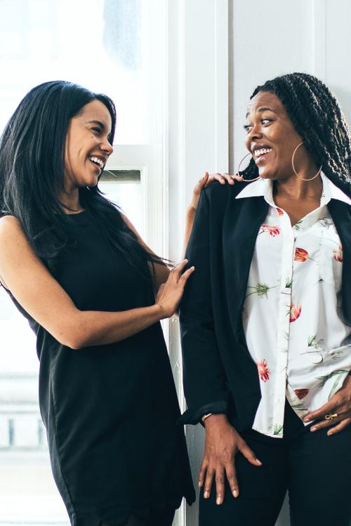 Two cheerful black women standing by the window - 1220812