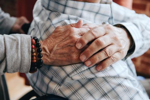 Elderly man on a wheelchair holding his wife hand on his shoulder - 1223778