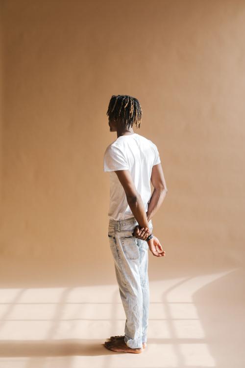 Black man standing by a beige background - 1226374