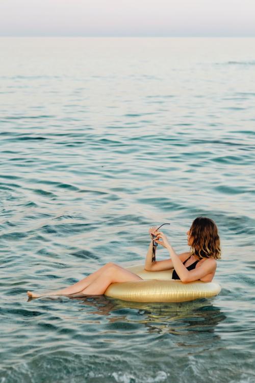 Girl sitting on a gold swim tube in the ocean - 1228372