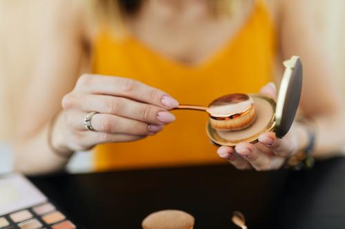 Beauty blogger applying oval cream puff to contour powder - 1232118