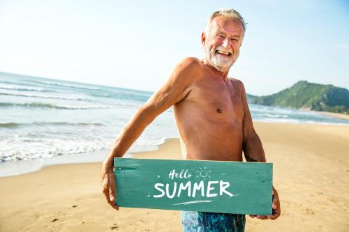 Senior man holding a signboard at the beach - 428589