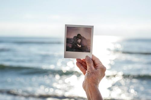 Old lady holding a photograph at the beach - 428698