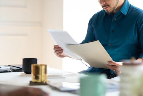 Businessman sitting on his desk reading a document - 1220971