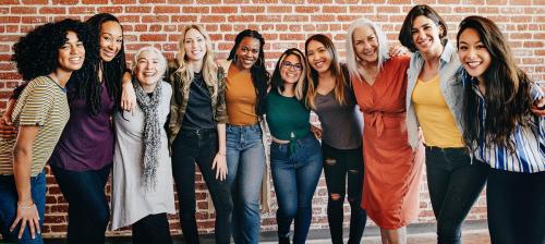 Cheerful diverse women standing in front of a red brick wall - 1223885