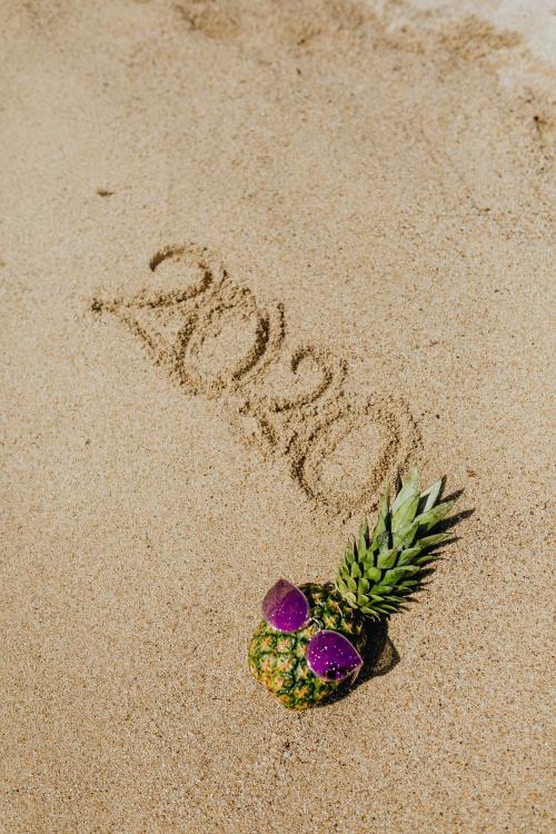 Cool pineapple wearing a purple sunglasses with a year 2020 word on the beach - 1228479