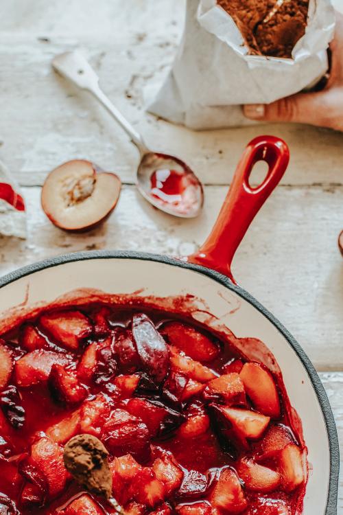 Woman adding cocoa powder to plums - 893680