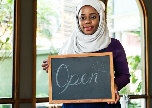 Islamic woman small business owner holding blackboard with smiling - 399963