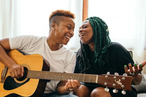 Happy lesbian couple playing the guitar and singing - 1205375