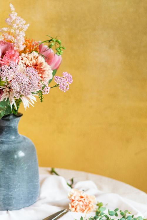 Flowers in a vase by a yellow wall - 1207129