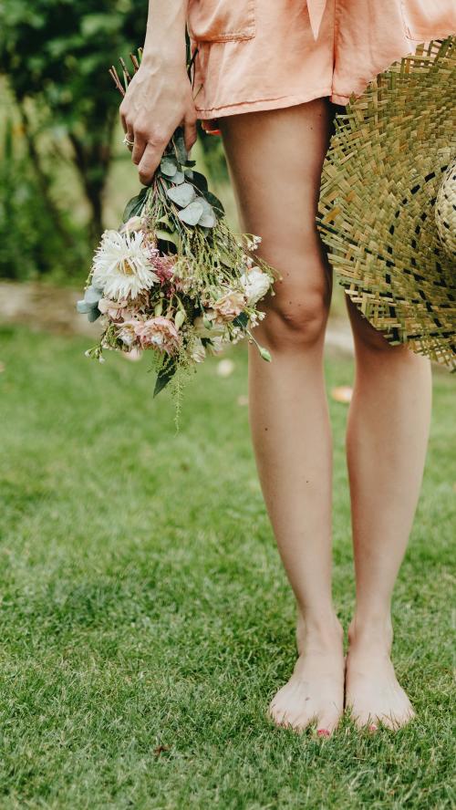 Woman in an orange jumpsuit with a bouquet of flowers - 1207917