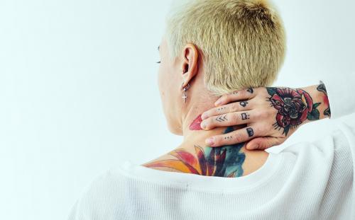 Tattooed woman touching her neck - 1212570