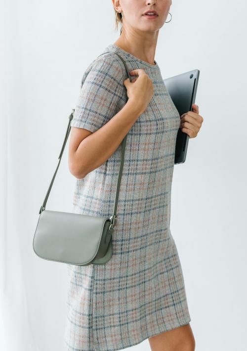 Woman in a gray plaid dress holding a laptop - 1212651