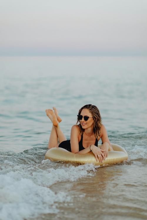 Girl lying on a gold swim tube at the beach - 1228373