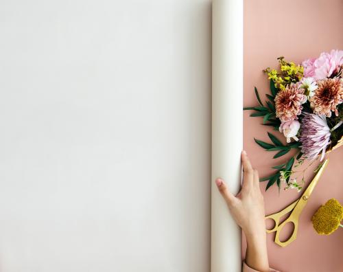 Florist rolling out a white banner on a pink desk - 1207334