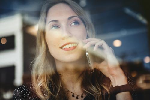 Happy woman on the phone looking out the window - 1208418