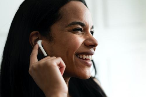 Cheerful woman enjoying music through a wireless earphone - 1208635