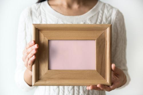 A woman holding blank wooden picture frame - 296435