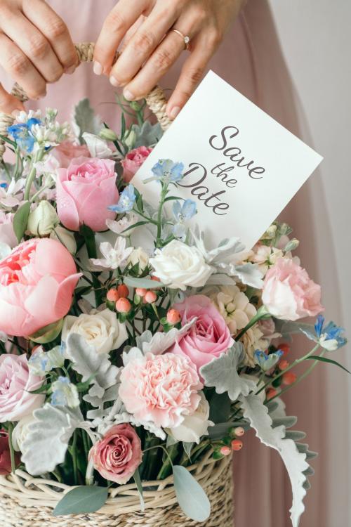 Hand carrying a basket filled with assorted colorful flowers and a note card - 1207504