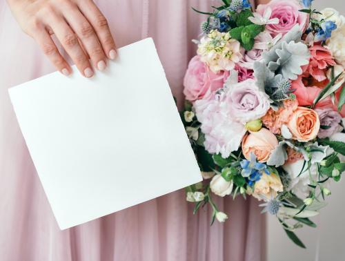 Bride holding a save the date card with a bouquet of flowers - 1207534