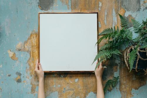 Woman holding a blank frame against a grungy wall - 1207720