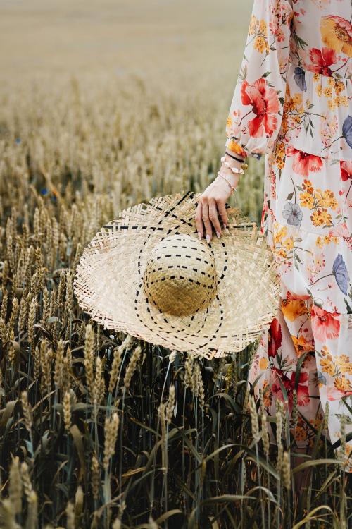 Woman in a floral dress with a woven hat in a field - 1207922