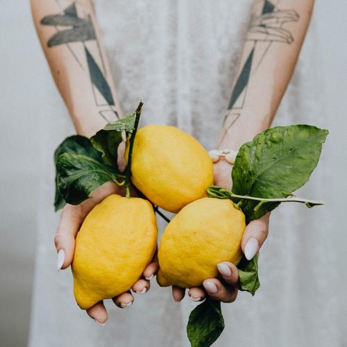 Tattooed hands holding fresh lemons - 1207944