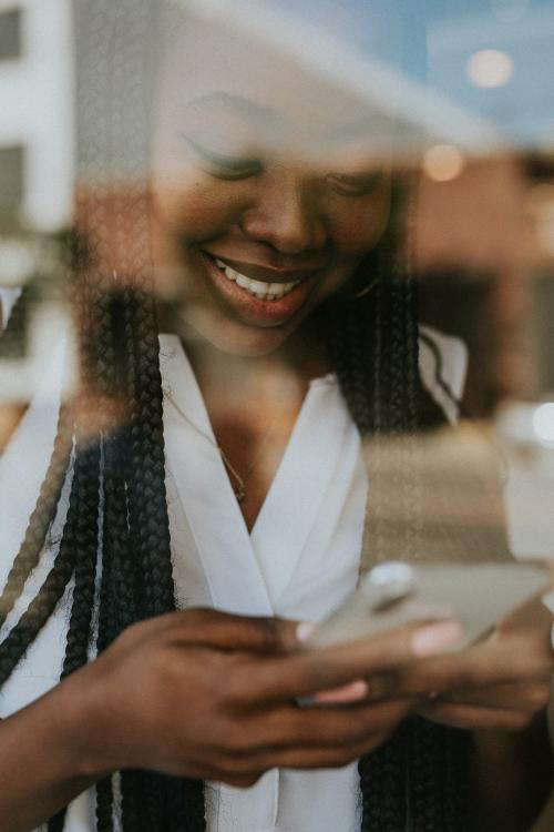 Cheerful black woman texting on her phone - 1208301