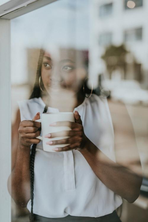 Woman enjoying a cup of coffee while looking out the window - 1208320