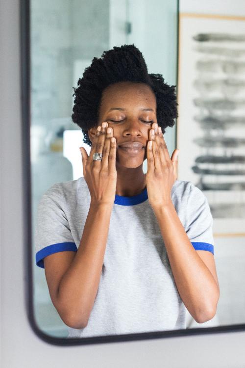 African woman standing by a mirror in a bathroom - 1211656