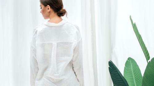 Woman in a white shirt standing by strelitzia plant - 1212646