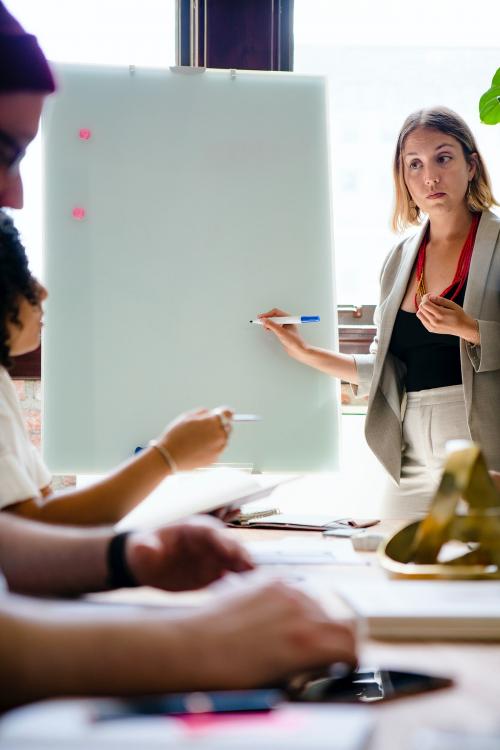 Businesswoman writing on a board in the meeting room - 1213740