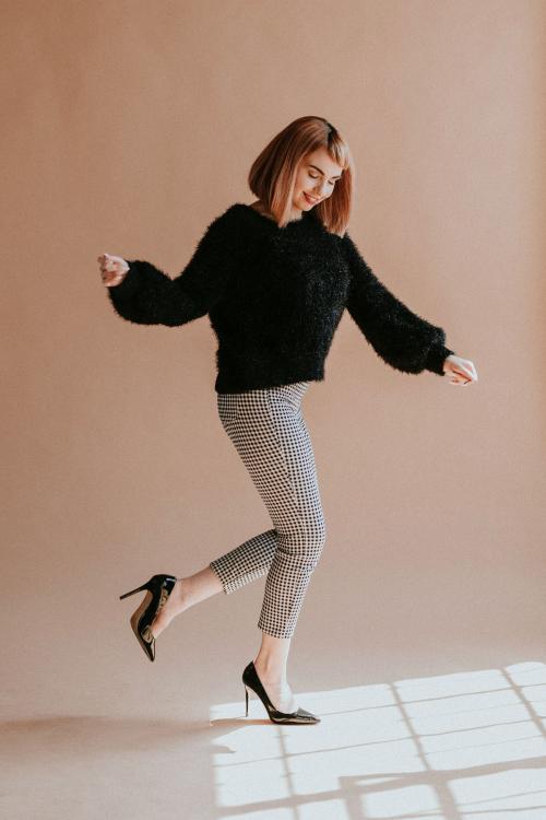 Brown hair woman in a black fluffy sweater hopping with high heels - 1216407