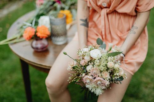 Woman in an orange jumpsuit with a bouquet of flowers - 1207865