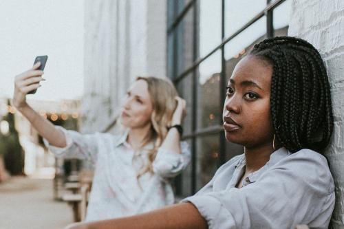 Black woman getting bored of her blond friend keep taking a selfie - 1208505