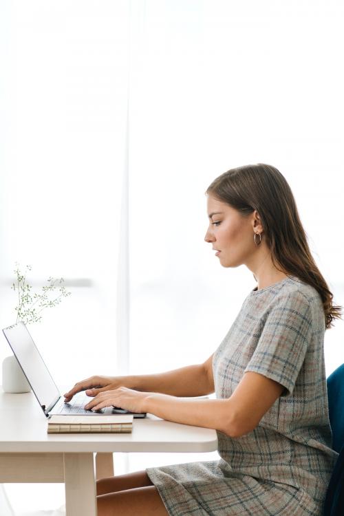 Businesswoman typing on her laptop on a wooden table - 1212613