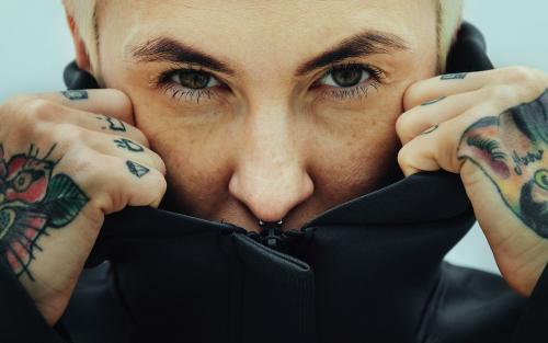 Tattooed woman covering her face with a black hoodie - 1212665