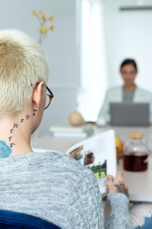 Blonde woman with tattoo reading a book - 1212749