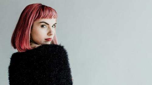 Brown hair woman in a black fluffy sweater looking back over her shoulder - 1216487