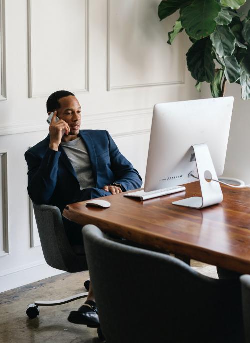 Casual businessman talking on a phone while working in the office - 1216657