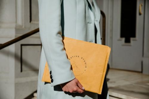 Woman holding a brown envelope mockup in front of a building - 1198666