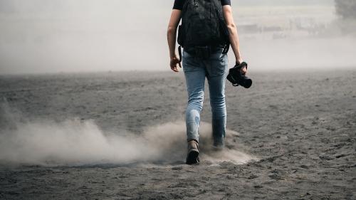 Rear view of a man walking on dusty land - 1198835