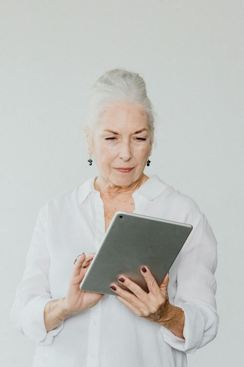 Senior woman using a digital tablet in a white room - 1201726