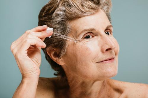 Senior woman applying moisturizer on her eye wrinkles - 1203166