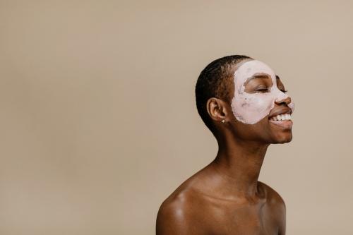 Happy black woman doing a face mask - 1203395