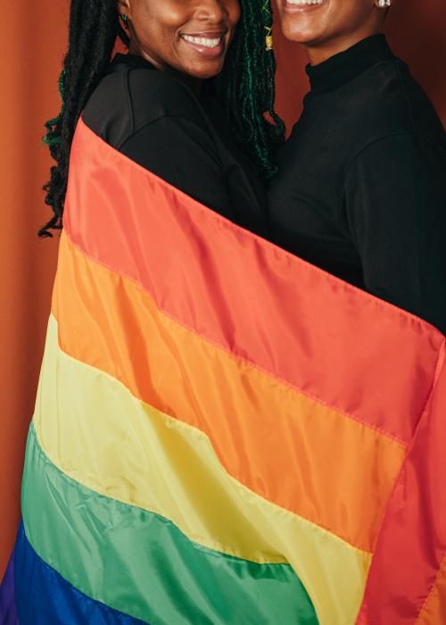 Happy lesbian couple with a colorful flag - 1205333