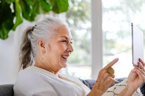 Elderly woman using a tablet on a couch - 1211823