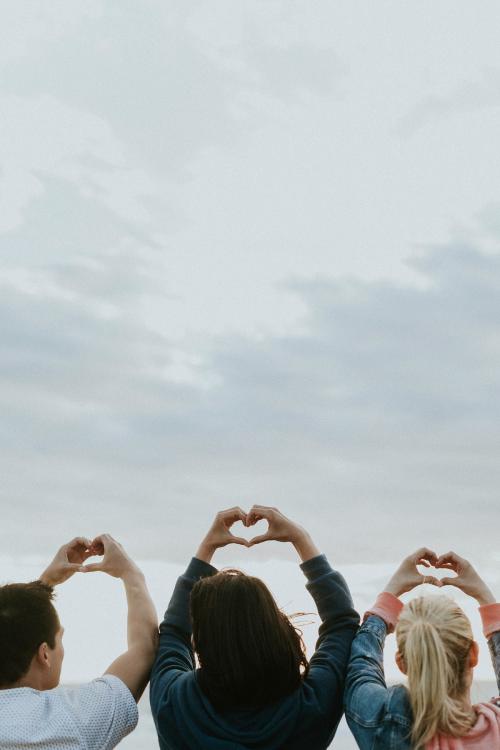 Friends making love heart hands at the beach - 1079745